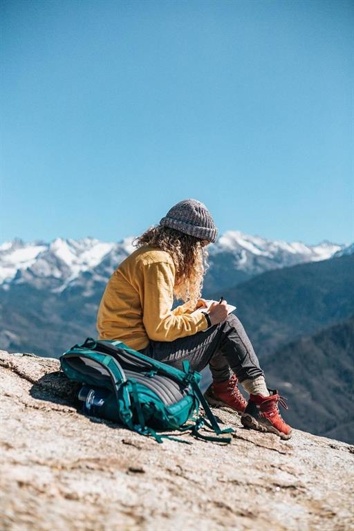 زنی رو به کوه ها در حال یادداشت کردن