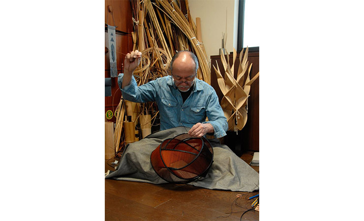 Japanese artist Fujitsuka Shosei works on a bamboo basket in his studio