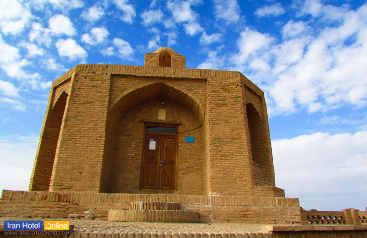 تصویری زیبا از معماری باشکوه آرامگاه ابن حسام خوسفی با نمای آجری، زیر سقف آسمان نیمه ابری و پاک