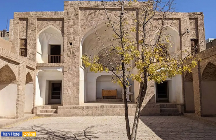 تصویری از بنای تاریخی خواجه نظر با معماری چشم‌نواز، نمای آجری و درختی خزان زده در حیلط