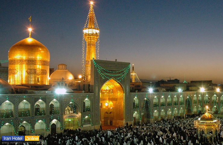 حرم امام رضا در شب و زائرانی که برای زیارت در صحن نشسته‌اند