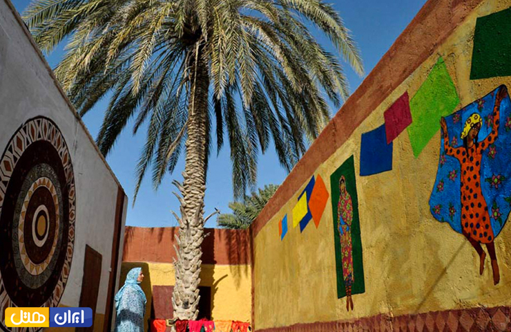 تصویری زیبا از نقاشی‌های رنگارنگ بر روی دیوار موزه نادعلیان و درخت نخلی در کنار آن