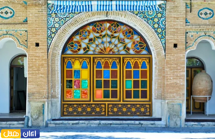 درب چوبی با پنجره‌های رنگارنگ در قلعه تاریخی والی ایلام